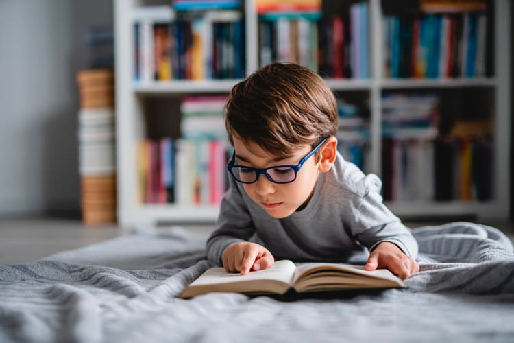 Niño con gafas leyendo un libro